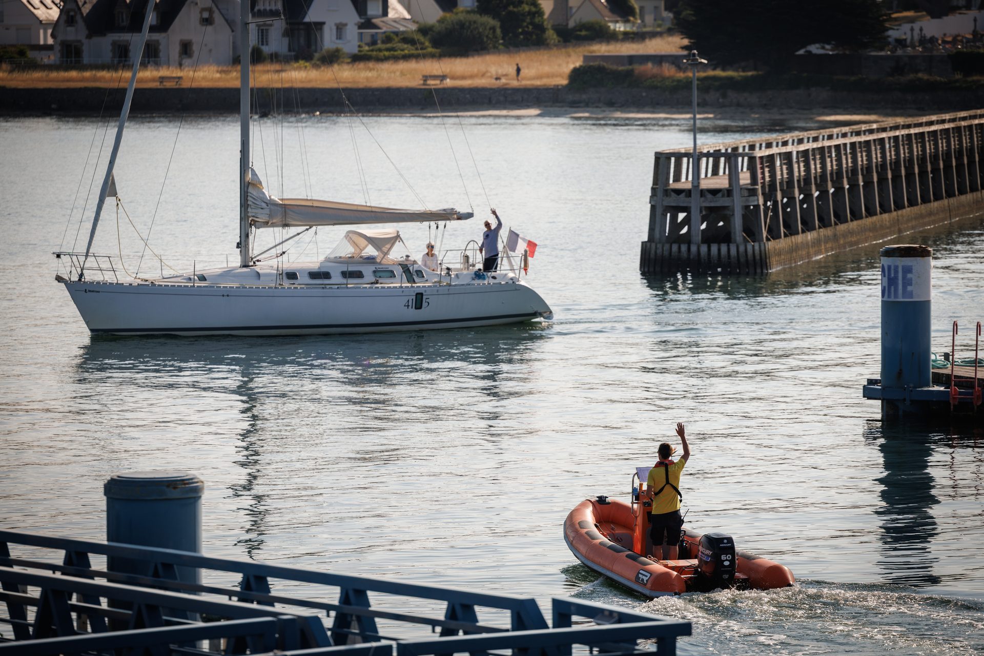 Un agent de port salue un plaisancier qui part en mer au départ de Port-Louis.
